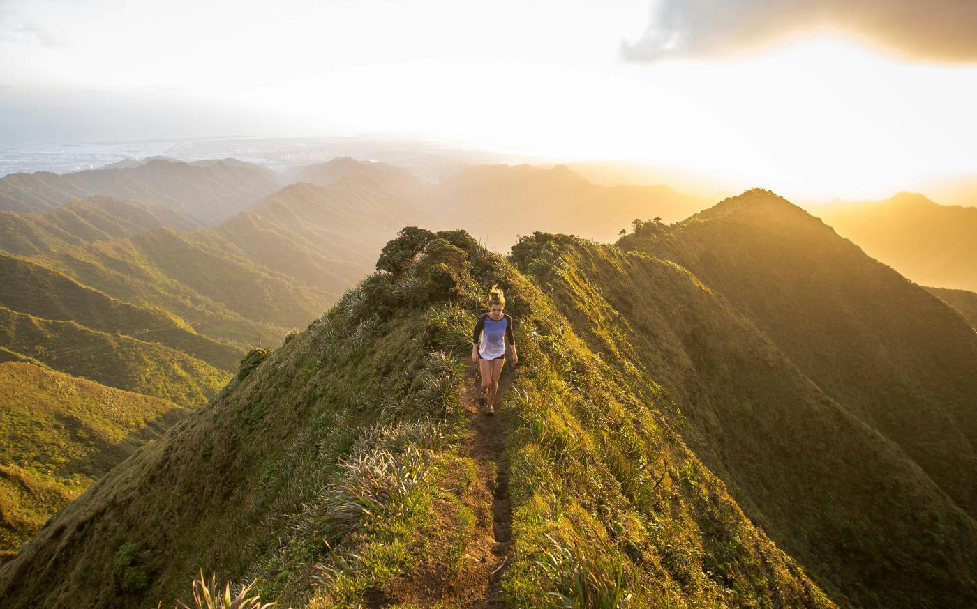 woman walking on pathway on top of hill at golden hour by Kalen Emsley courtesy of Unsplash.