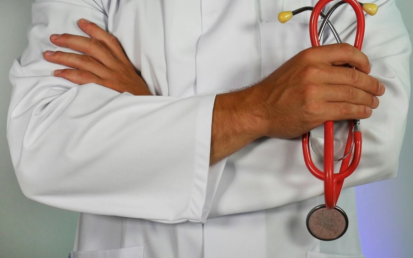 doctor holding red stethoscope by Online Marketing courtesy of Unsplash.